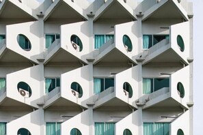 Un immeuble à plusieurs étages doté d’une façade géométrique, agrémentée de balcons et de fenêtres rondes.