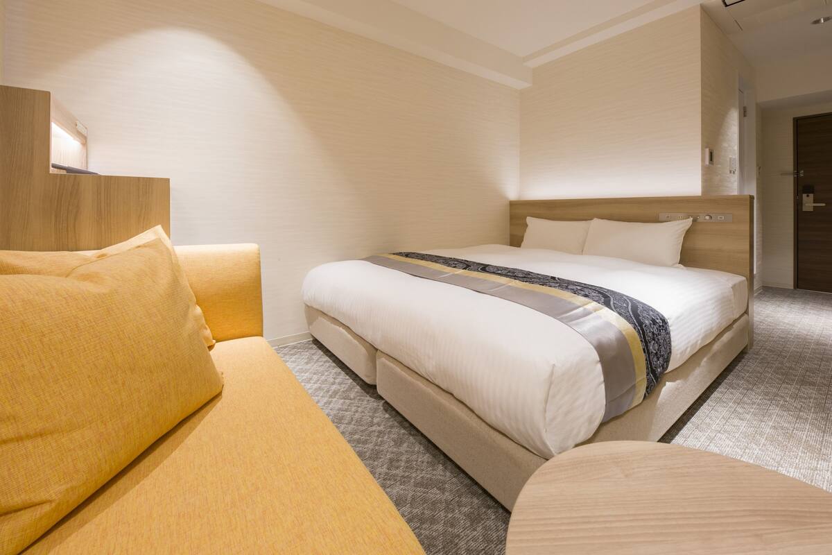 A hotel room with a bed, a sofa, and a wooden headboard.