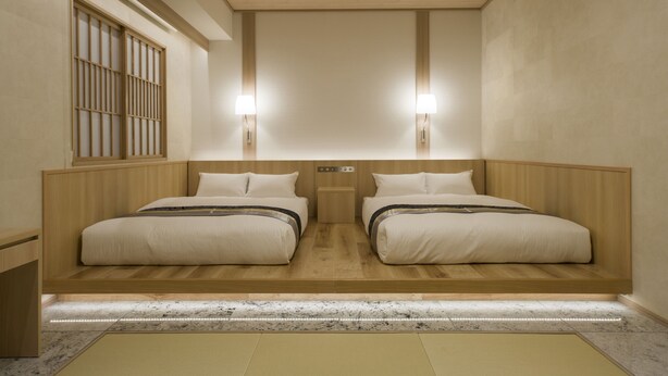 Quarto de hotel com duas camas, cabeceiras de madeira, pequenas mesas de cabeceira e duas luminárias fixadas na parede.