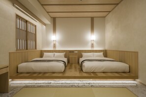 Habitación de hotel con dos camas, cabeceros de madera, mesitas de noche pequeñas y dos lámparas fijadas a la pared.