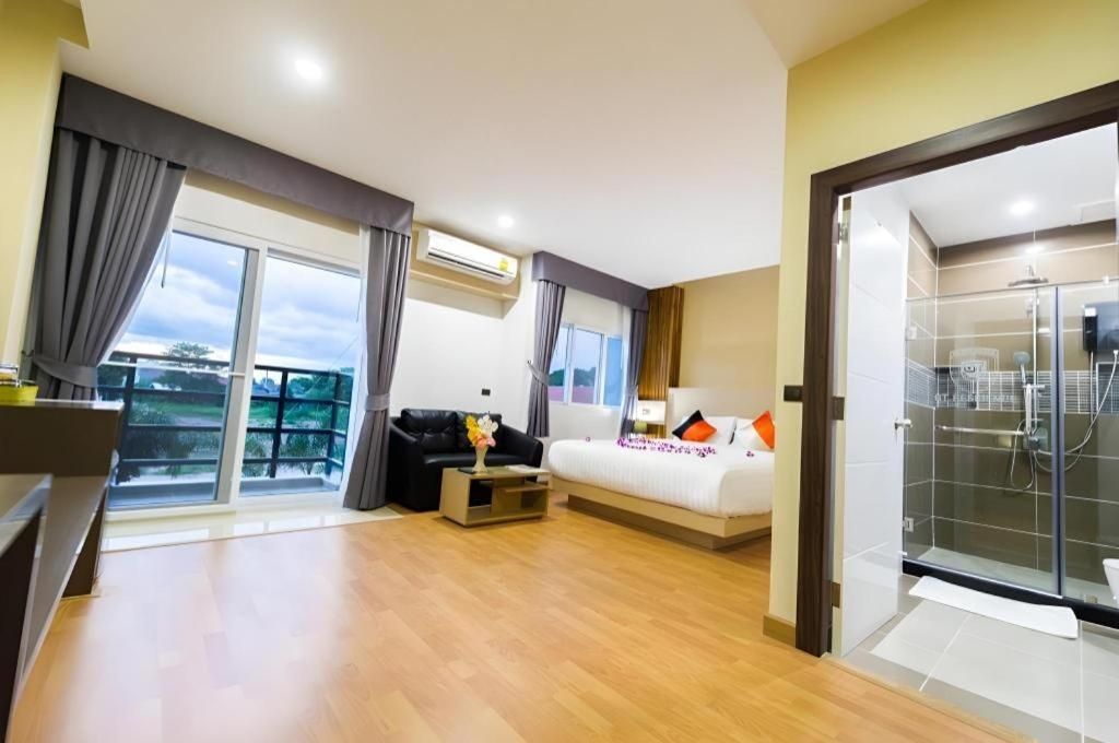 Una habitación de hotel con cama, sofá, mesa de centro y cabina de ducha con paredes de vidrio.
