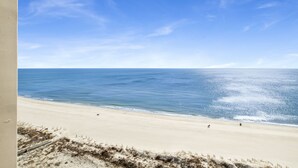 A beach with a clear sky, sandy shore, and a few people walking. - Beachfront 1BR @ Phoenix X • Sleeps 6 • Gulf Views, Pools & Next to Flora-Bama (Orange Beach)