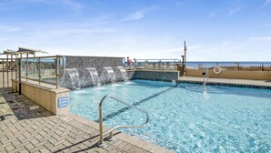 A swimming pool with a tiled deck, a lifeguard stand, and a view of the ocean. - Beachfront 1BR @ Phoenix X • Sleeps 6 • Gulf Views, Pools & Next to Flora-Bama (Orange Beach)