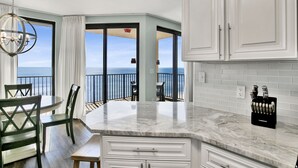 A kitchen with a marble countertop, white cabinets, and a view of the ocean. - Beachfront 1BR @ Phoenix X • Sleeps 6 • Gulf Views, Pools & Next to Flora-Bama (Orange Beach)