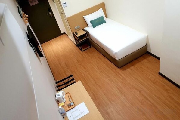A small hotel room with a single bed, a bedside table, and a wooden floor. - Qlio Hotel (Kota Kinabalu)