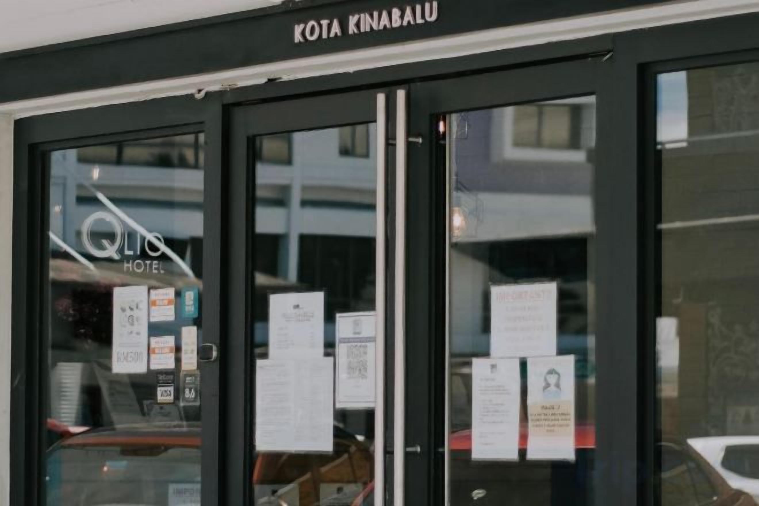 A hotel entrance with glass doors, a visible sign for 'QLIC Hotel,' and some posted notices.