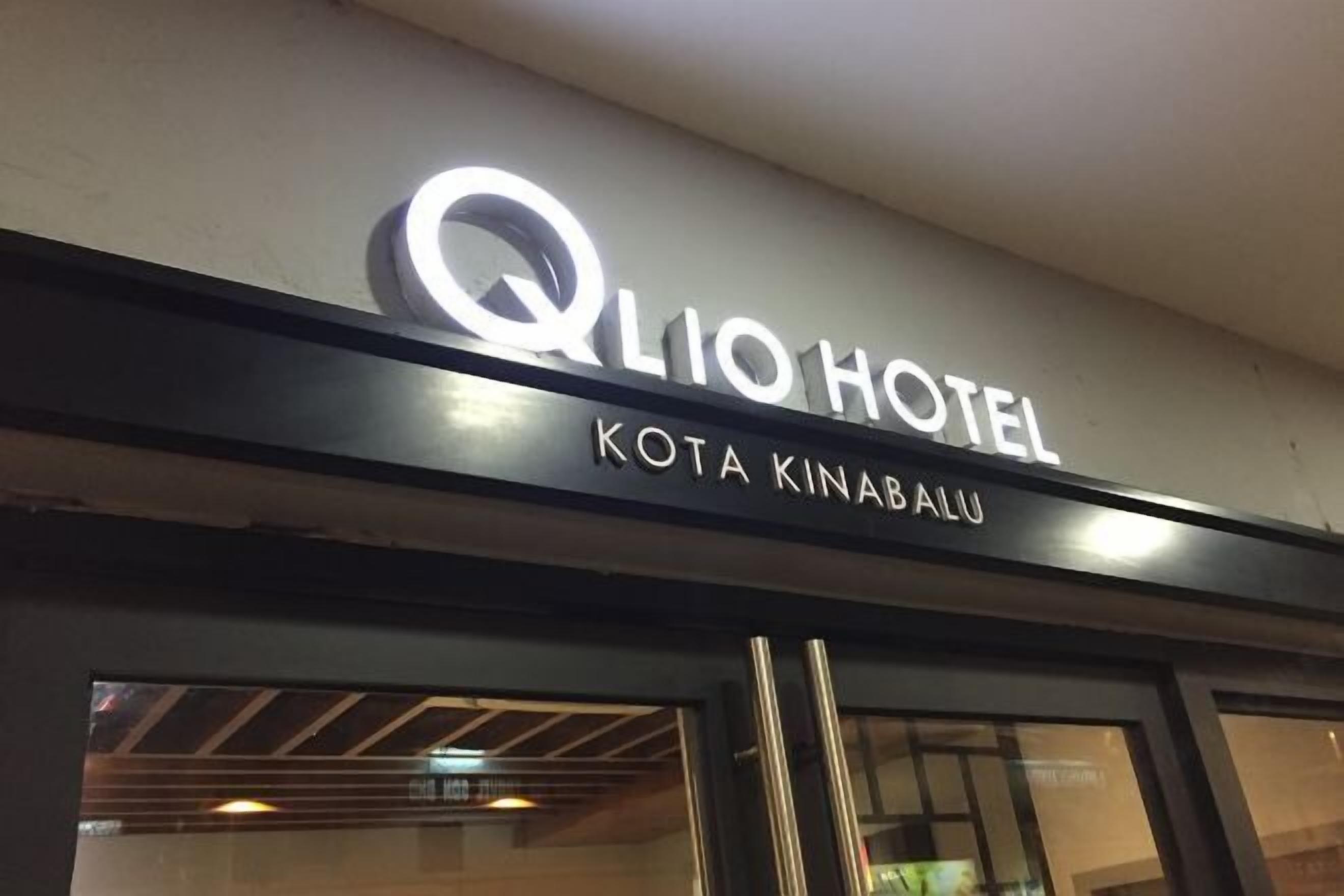 Exterior del HOTEL QLIO, con su nombre y ubicación "KOTA KINABALU" mostrados sobre la entrada.