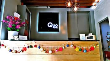 A hotel reception desk with a digital display, a clock, and a decorative garland.