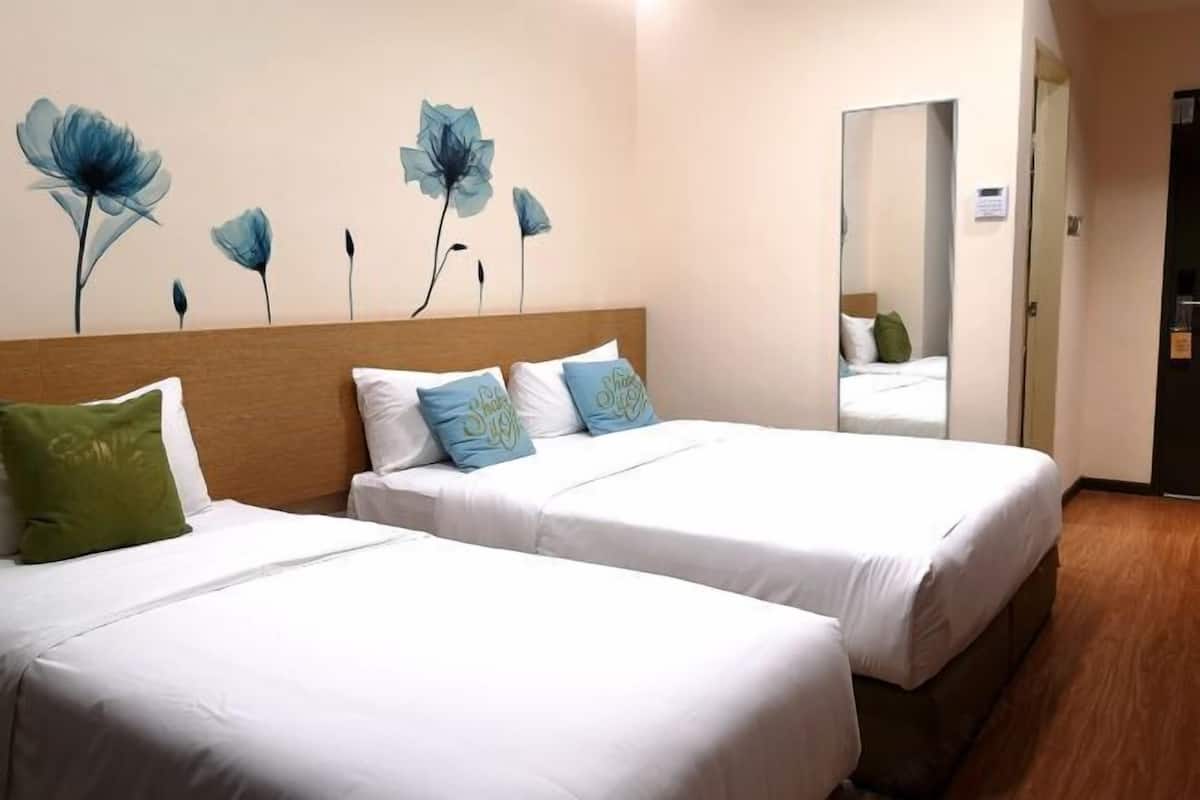 Et hotelværelse med to senge, et træhovedgærde og en væg med blomsterkunst.