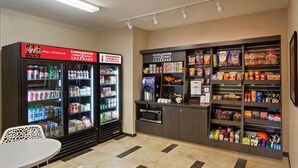 Un’area self-service con distributori di bevande, un forno a microonde e una selezione di snack e condimenti.