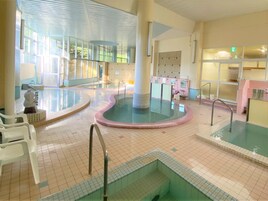 Un área de piscina interior con varias piscinas, un vestuario y una estatua.