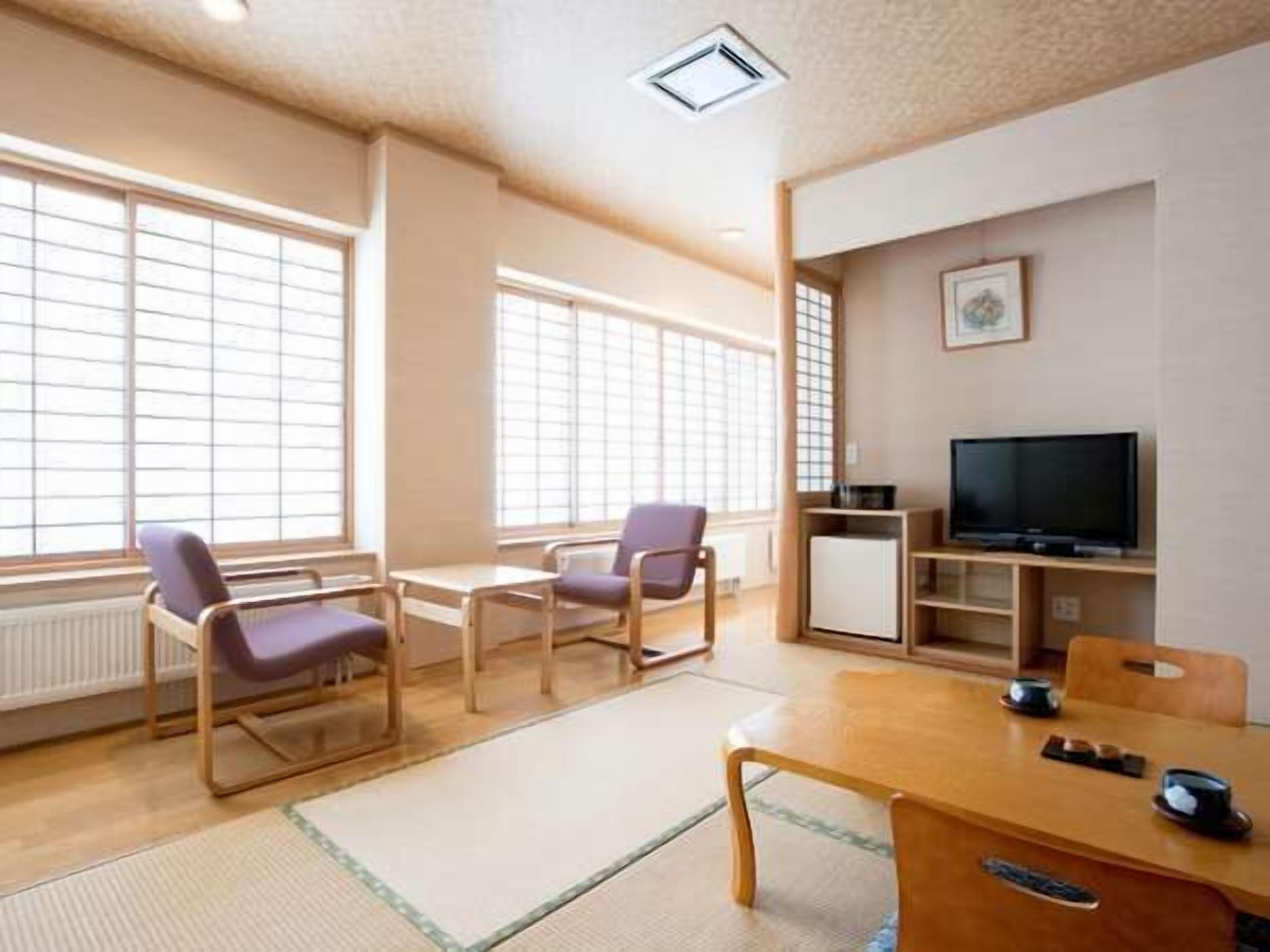 A room with a wooden table, chairs, a television, and a radiator.