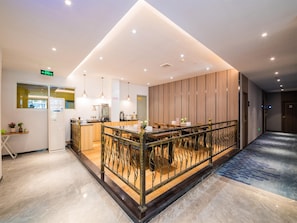 A modern hotel lobby with a central bar area, seating, and a reception desk.
