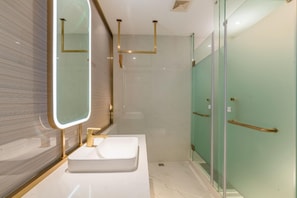 A modern bathroom with a white sink, a large mirror, and a glass shower enclosure.