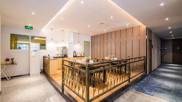 A modern hotel lobby with a reception desk, seating area, and a decorative railing.