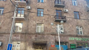 Un edificio de varios pisos con balcones, unidades de aire acondicionado y un local comercial con rótulos.