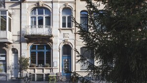 A historic building with ornate balconies, large windows, and a blue door.
