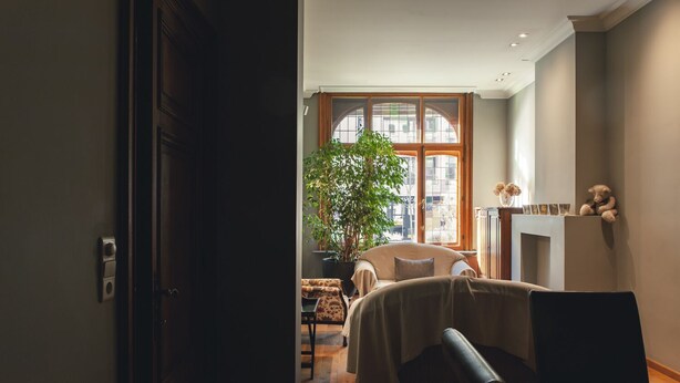 A cozy living room with a large window, a sofa, a coffee table, and a fireplace.