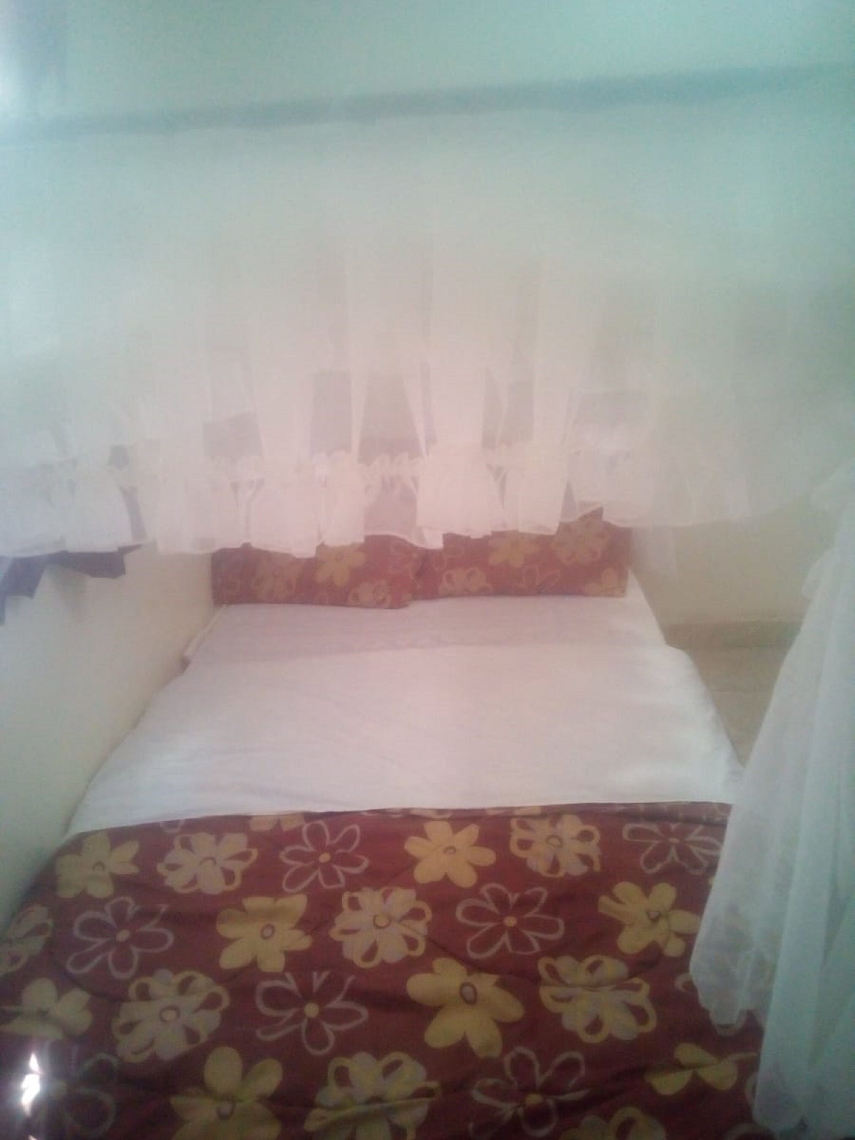 Una cama individual con un edredón estampado con motivos florales y falda para cama blanca.