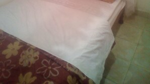A bed with a white bedspread and a floral-patterned blanket. - Jaws Palace Umoja (Nairobi)