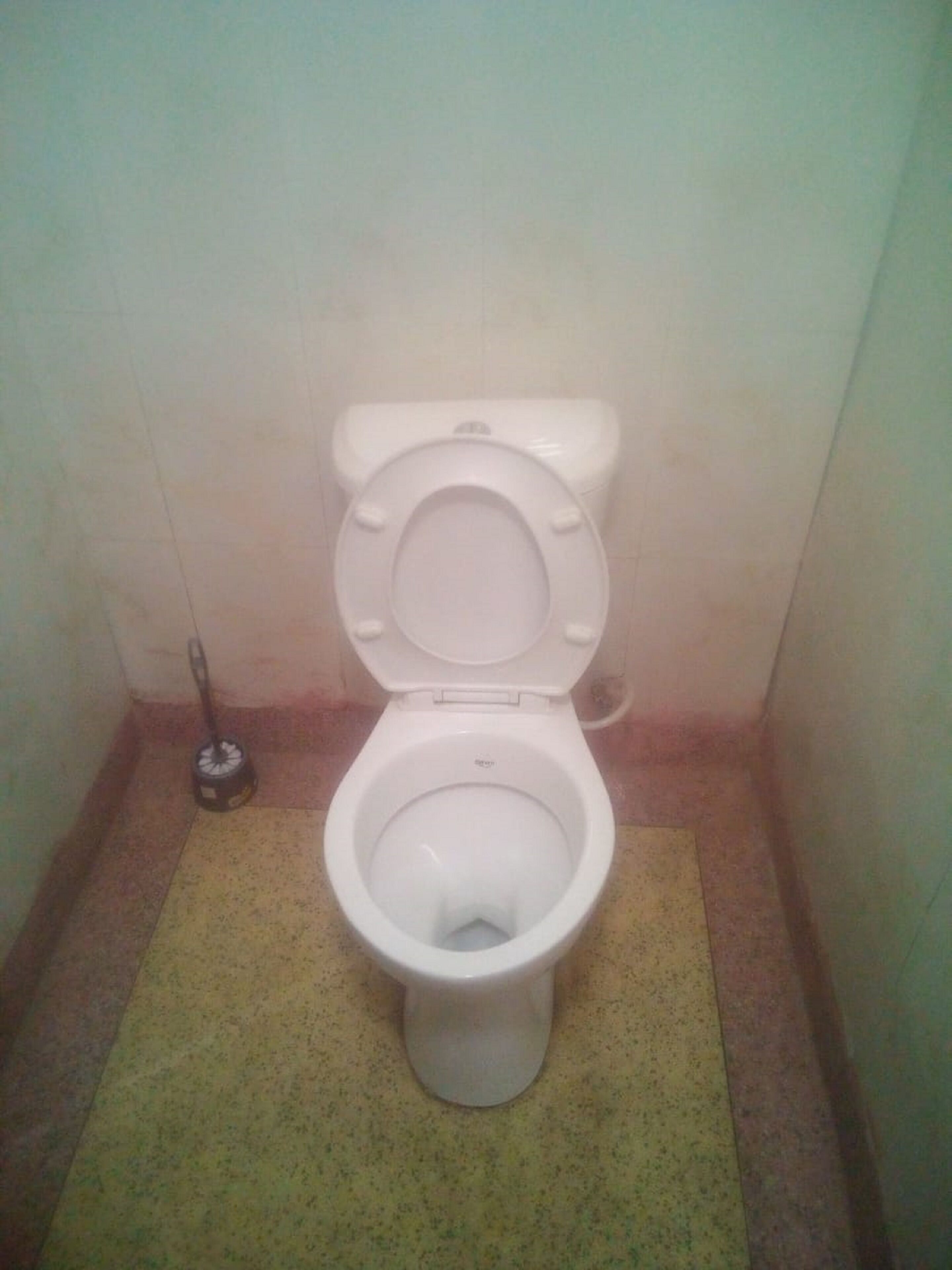 Un WC standard bianco con funzione bidet in un piccolo bagno piastrellato.