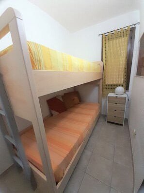 A bunk bed room with a desk and a lamp.