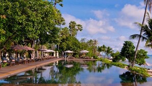 A pool with lounge chairs and umbrellas, surrounded by palm trees and a clear sky. - Saree Samui (Koh Samui)