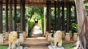 A pathway flanked by stone lion statues under a thatched roof structure, leading to a central staircase. - Saree Samui (Koh Samui)