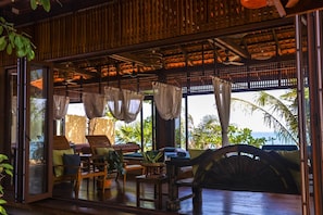Relax in this tropical retreat with ocean views, a wooden archway, and a ceiling fan.