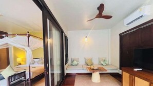 A modern hotel room with a bed, a sofa, a TV, and a ceiling fan. - Saree Samui (Koh Samui)