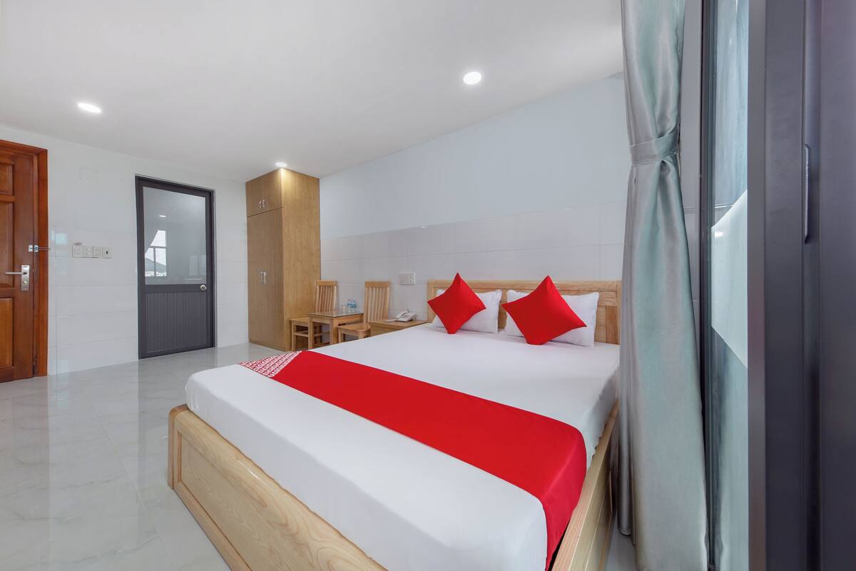 A modern hotel room with a large bed, a desk, and a shower area.