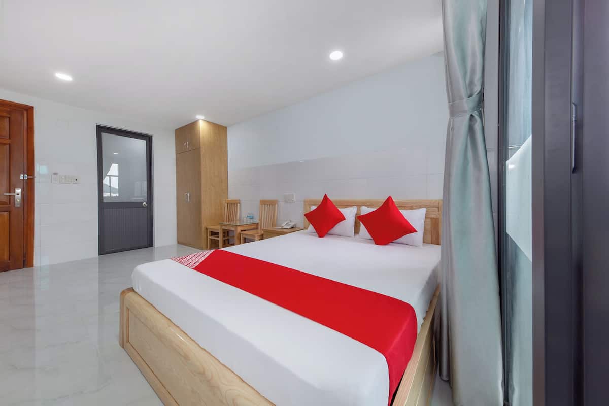 A modern hotel room with a large bed, a desk, and a shower area.