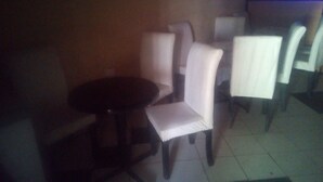 A dimly lit room with a round table and four chairs, one of which is partially obscured. - Soulfa Guest House (Nairobi)