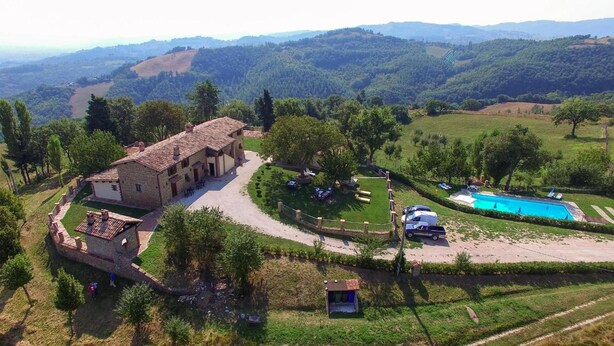 A villa with a courtyard, a swimming pool, and a view of the surrounding hills. - Agriturismo Casanova (Gubbio)