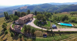 A villa with a courtyard, a swimming pool, and a view of the surrounding hills.