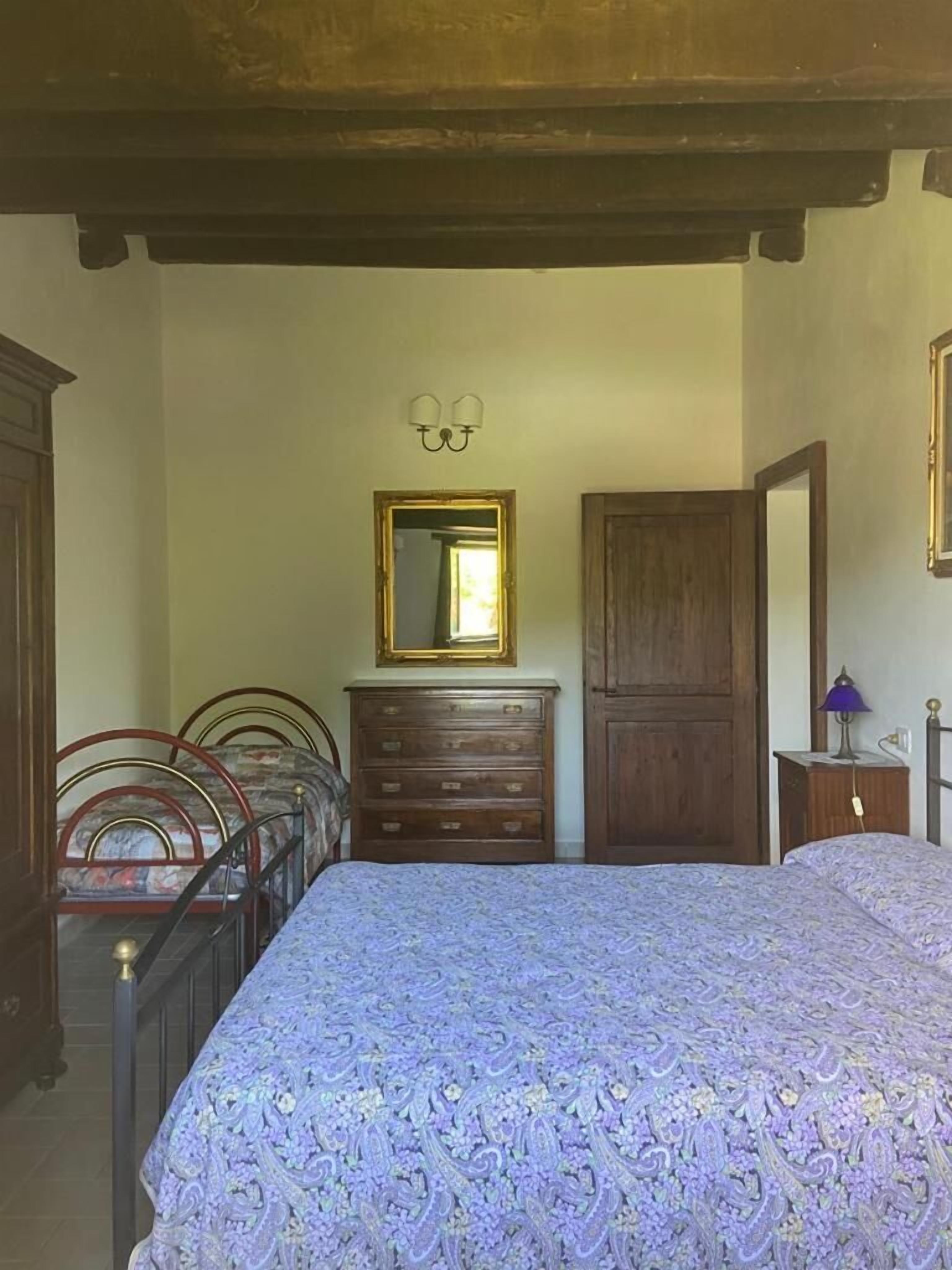 A bedroom with a large bed, a dresser, a mirror, and a wardrobe.