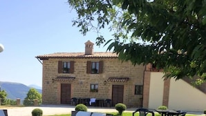 An outdoor seating area with wicker furniture and a wooden deck. - Agriturismo Casanova (Gubbio)