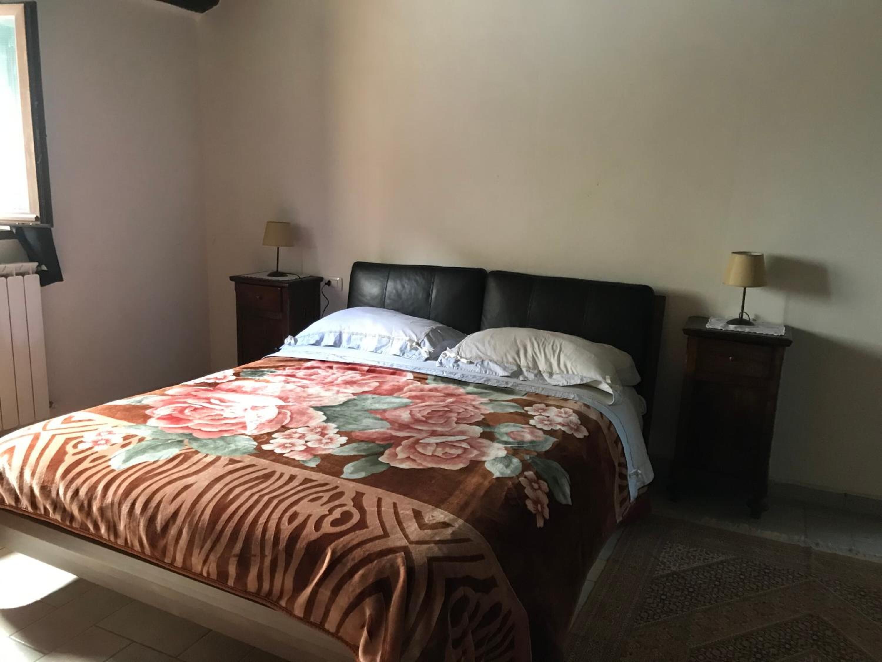 A bedroom with a bed, two bedside tables, and a window.