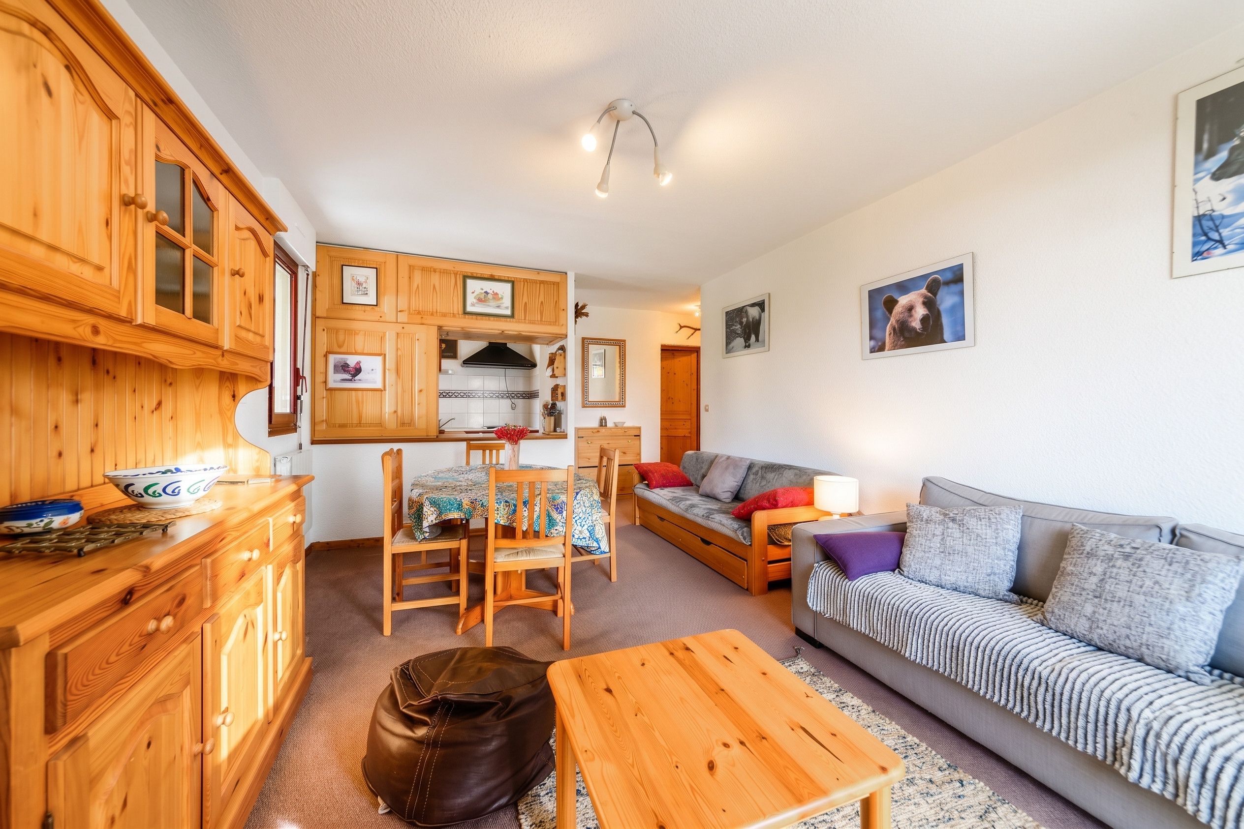 Una sala acogedora con sofá, una mesa de comedor con sillas, armarios de madera y una zona de cocina con estufa.