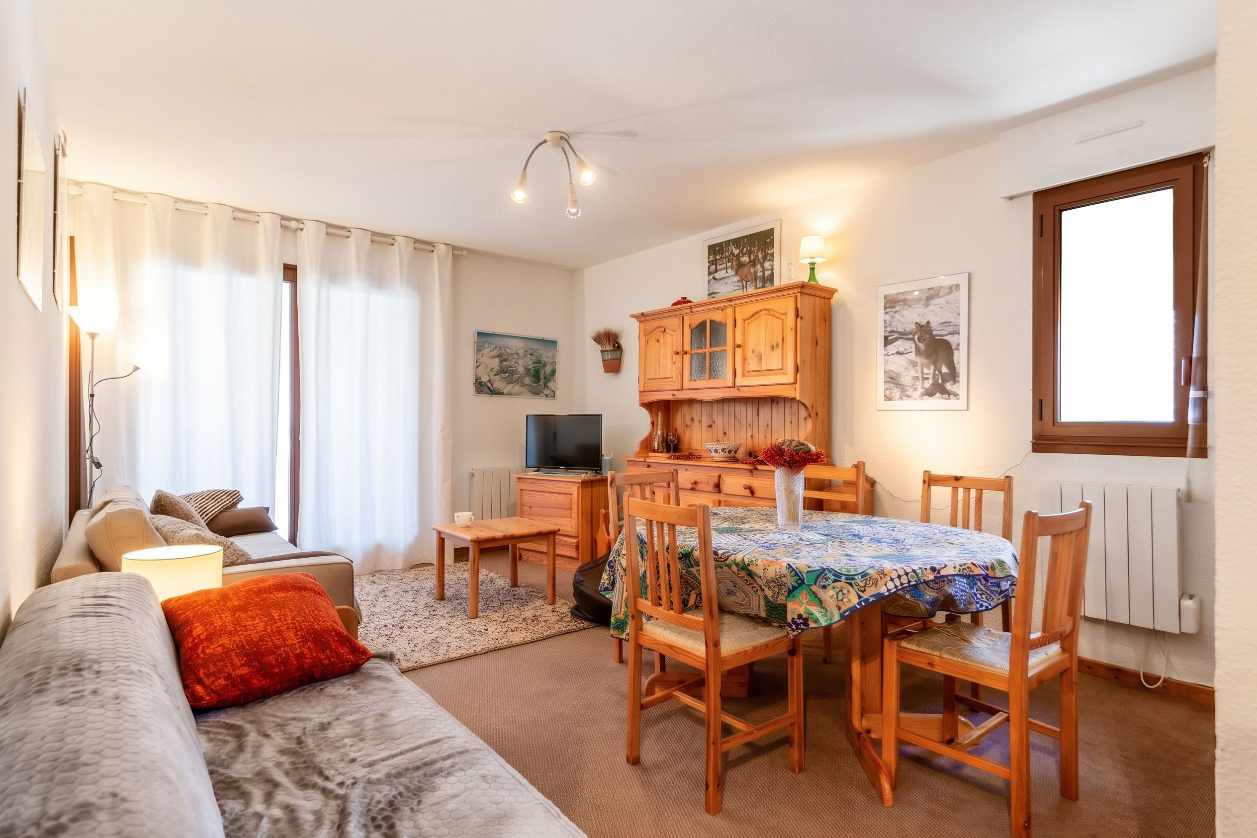 Una sala acogedora con sofá, una mesa de comedor con sillas, televisor y chimenea.