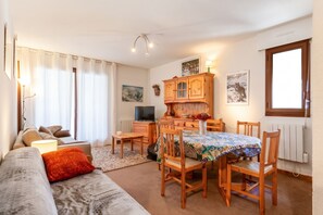 A cozy living room with a sofa, a dining table with chairs, a TV, and a fireplace. - Homerez - Apartment in Bolquère, mountain view (Bolquère)