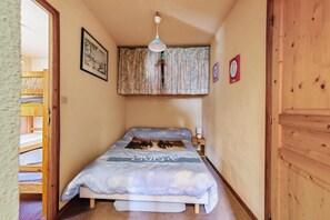 A bedroom with a bed, a wooden door, a wall clock, and a ceiling light. - Homerez - Apartment in Bolquère, mountain view (Bolquère)