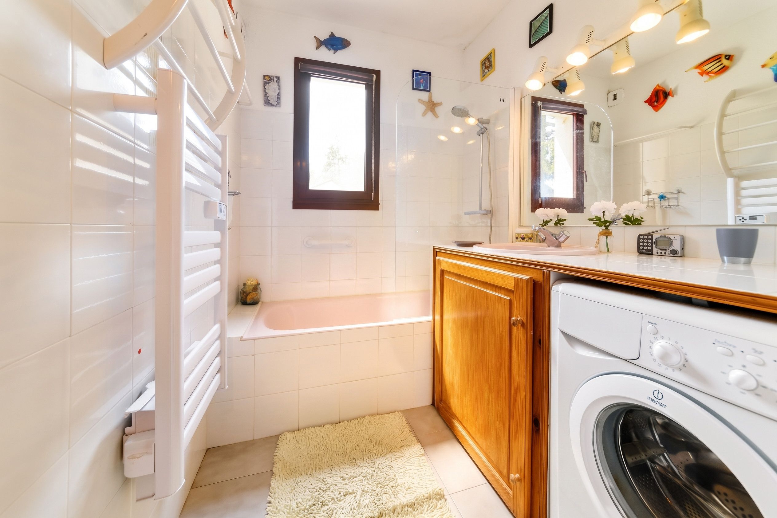 A modern bathroom with a bathtub, a washing machine, and a large mirror.