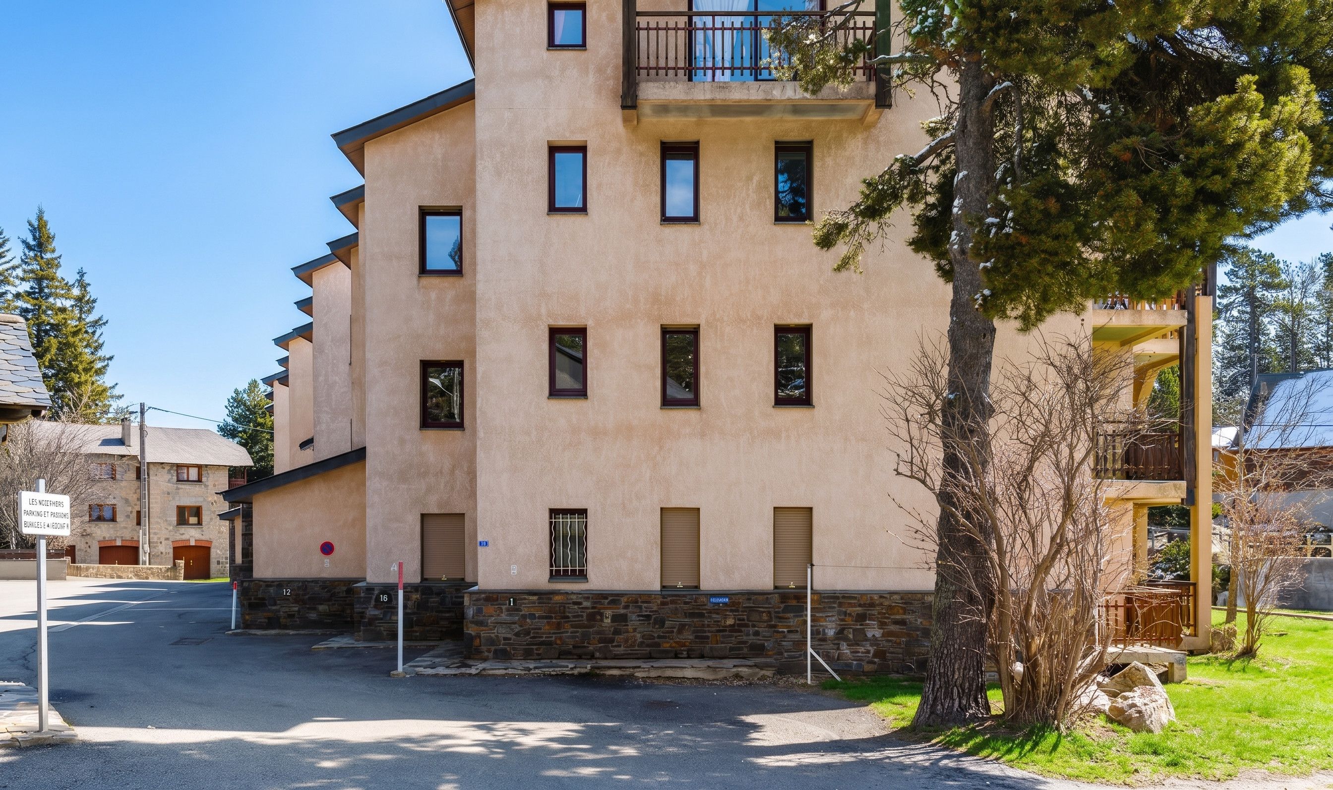 A multi-story building with a stone base, multiple windows, and a balcony.