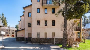 A multi-story building with a stone base, multiple windows, and a balcony.