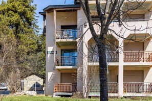A multi-story building with balconies, a stone structure to the left, and a tree in the foreground. - Homerez - Apartment in Bolquère, mountain view (Bolquère)