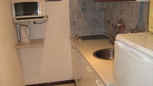 Een kleine keuken met een magnetron, spoelbak en koelkast.