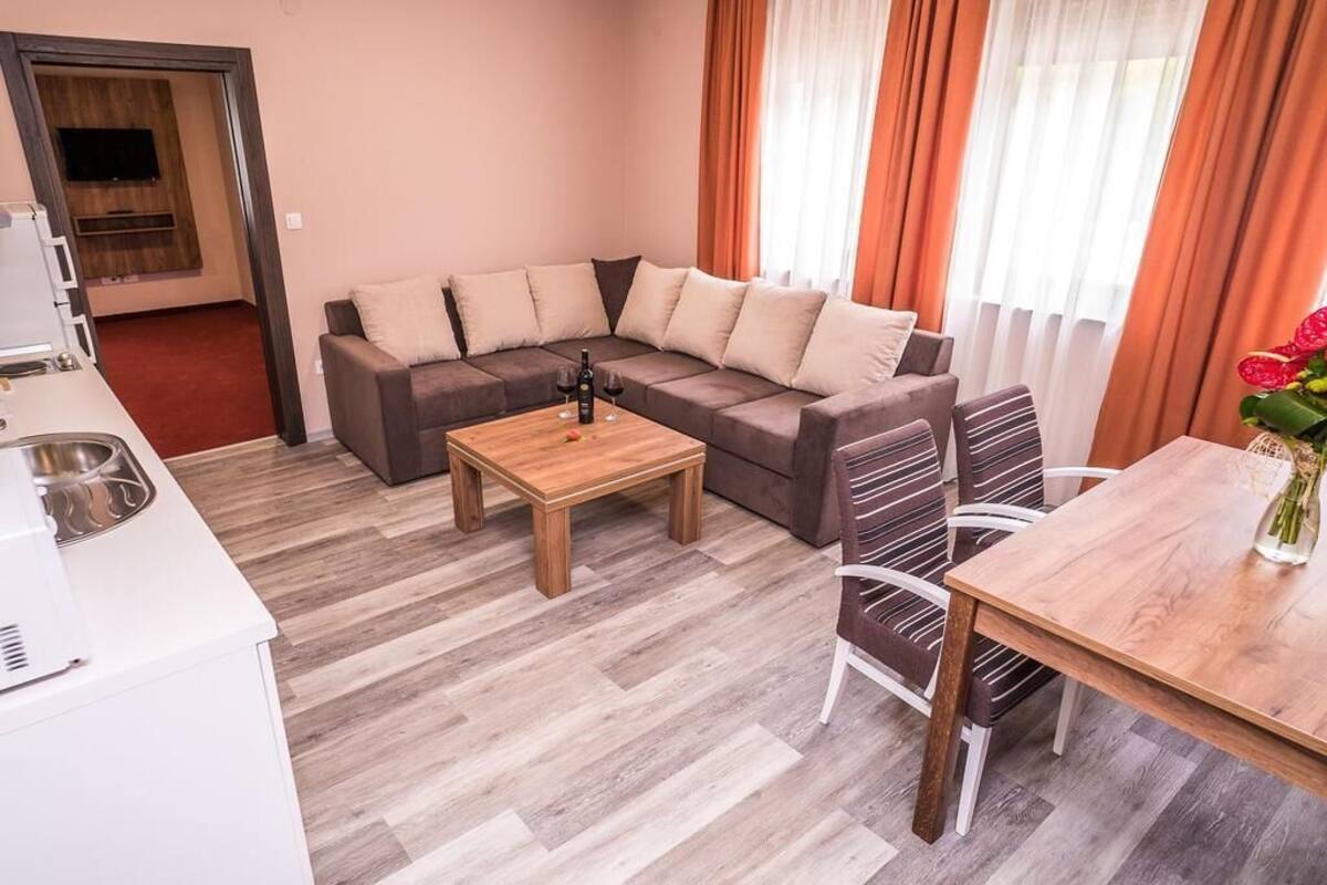 A modern living room with a sectional sofa, a wooden coffee table, and a dining area with a table and chairs.
