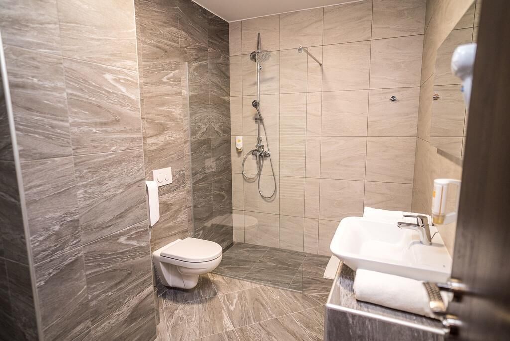 A modern bathroom with a shower, toilet, and sink.