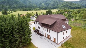 A large, two-story house with a sloped roof, surrounded by a well-maintained lawn and a dense forest. - Villa Angy (Plitvicka Jezera)